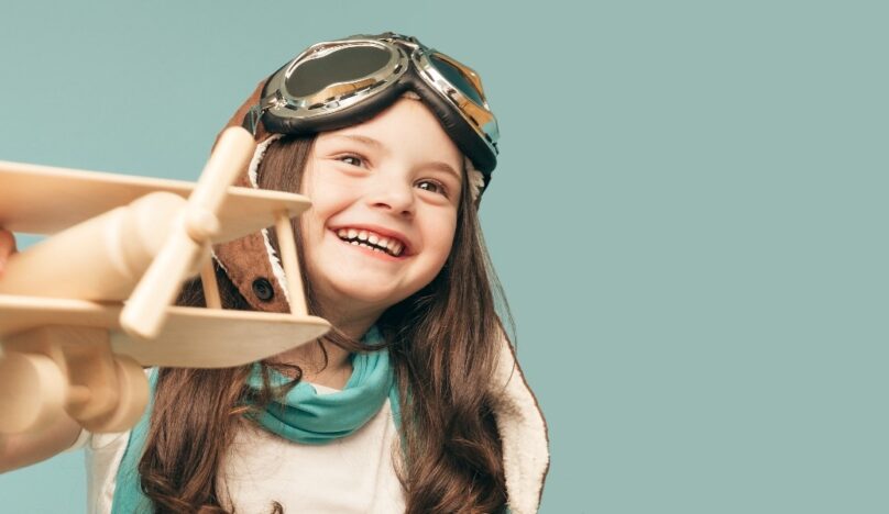 Little girl dressed as a pilot with model aeroplane